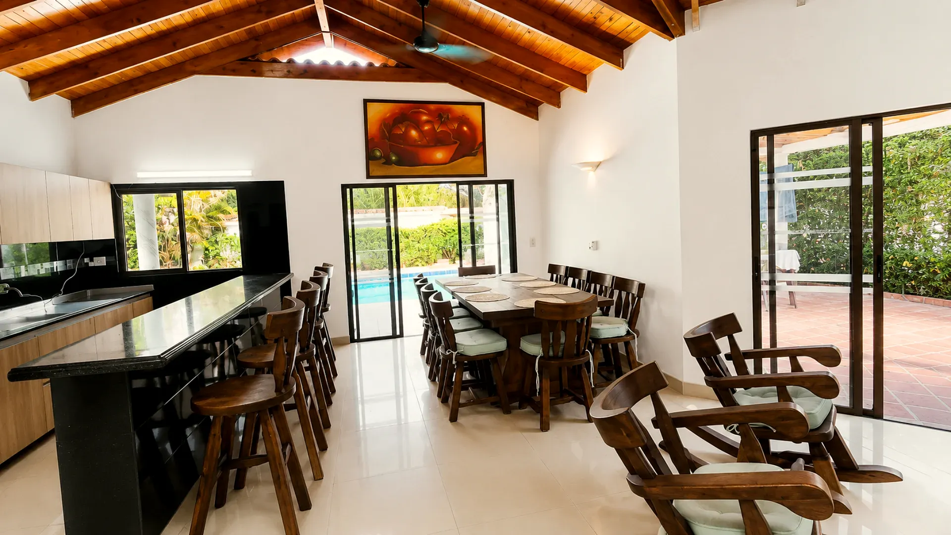 Cocina integral con barra y comedor amplio, con vista a la piscina