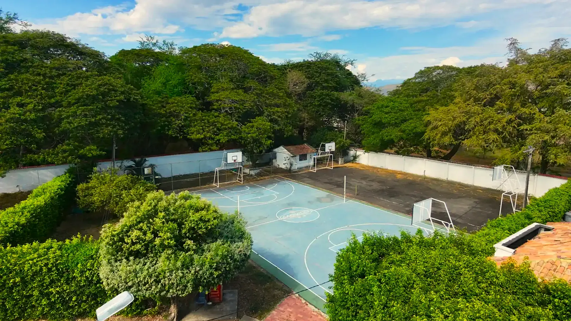 Canchas de baloncesto y microfútbol del condominio, rodeadas de árboles