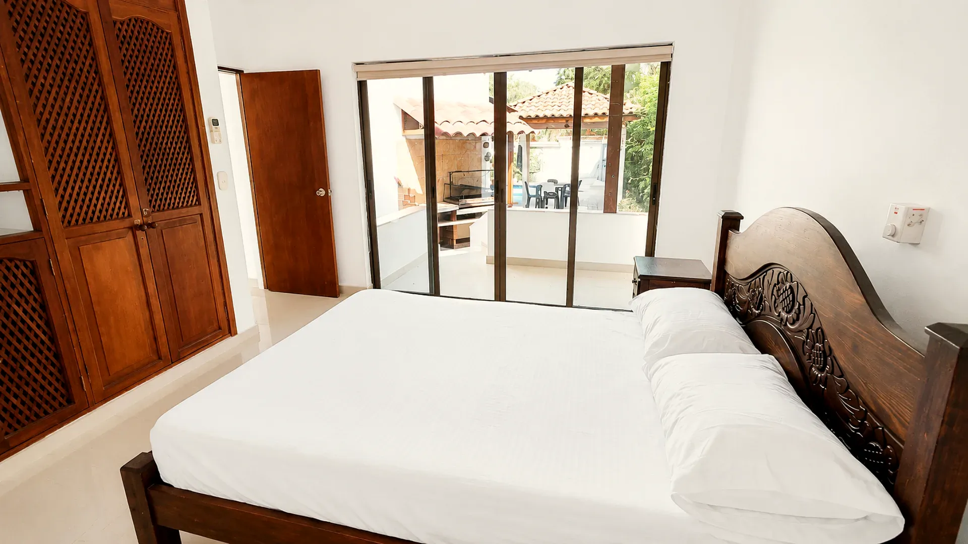 Habitación principal con cama doble, clóset de madera y salida al corredor