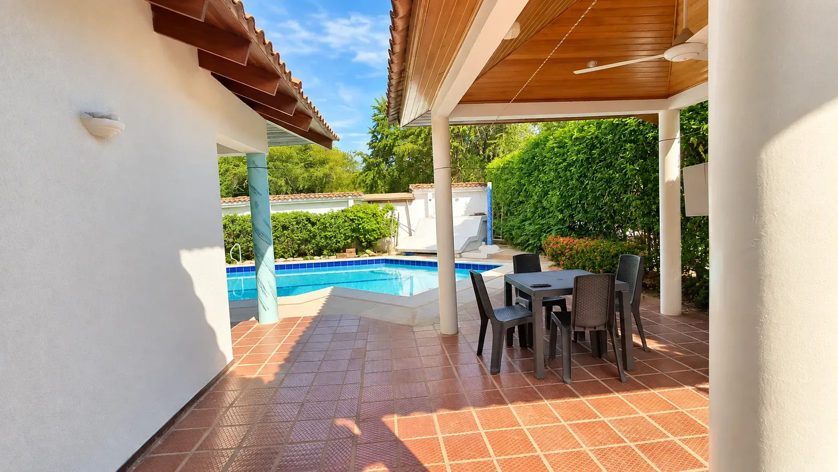Corredor cubierto con mesa de comedor junto a la piscina privada